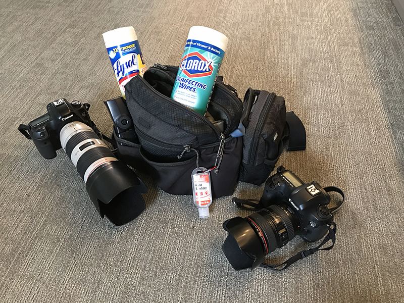 Camera bag with two canisters of disinfecting wipes and a bottle of hand sanitizer