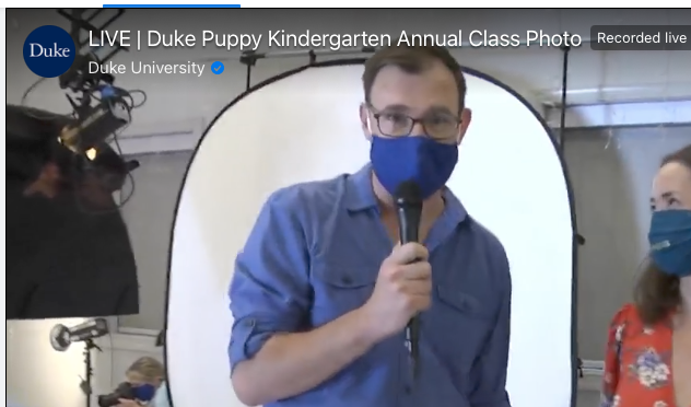 A screenshot from the Facebook Live Duke Puppy Kindergarten class photo video shows colleague Greg Phillips, director of global communications, interviewing Vanessa Woods, director of the Duke Puppy Kindergarten.