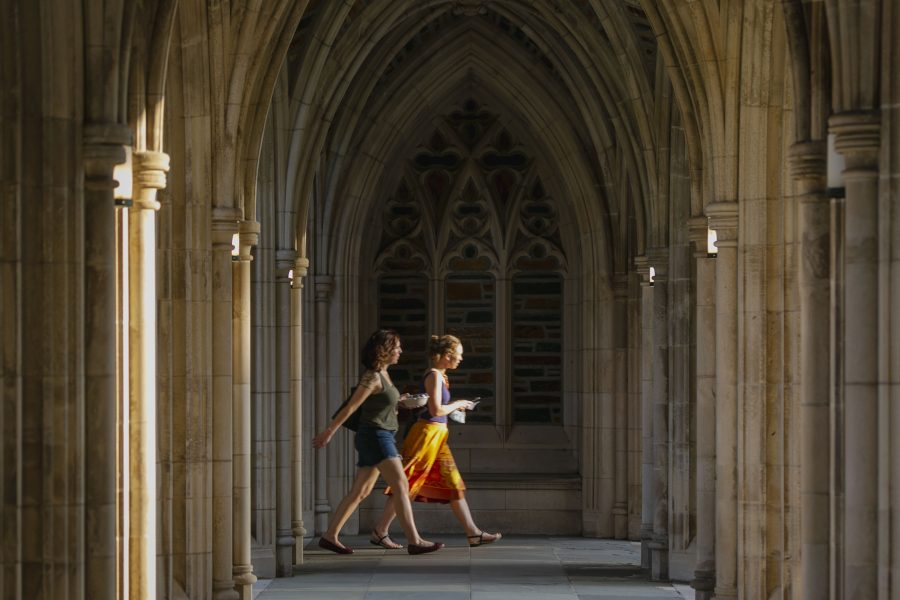 Folks walk through the arches of the Chapel arcade during a summer evening.